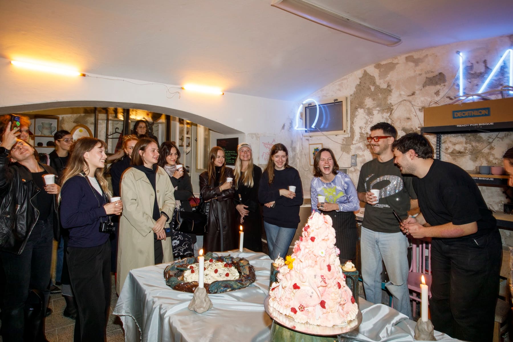 Guests at an evening event in the studio, around a table with a decorated cake