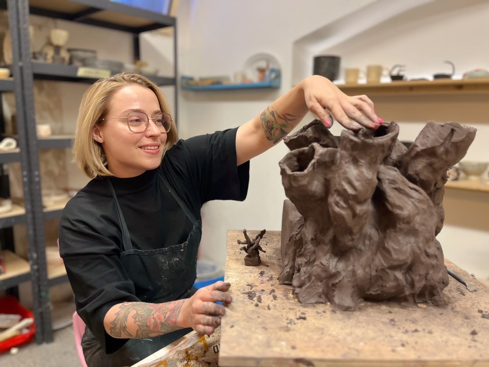 A studio member building a large sculptural clay vessel by hand
