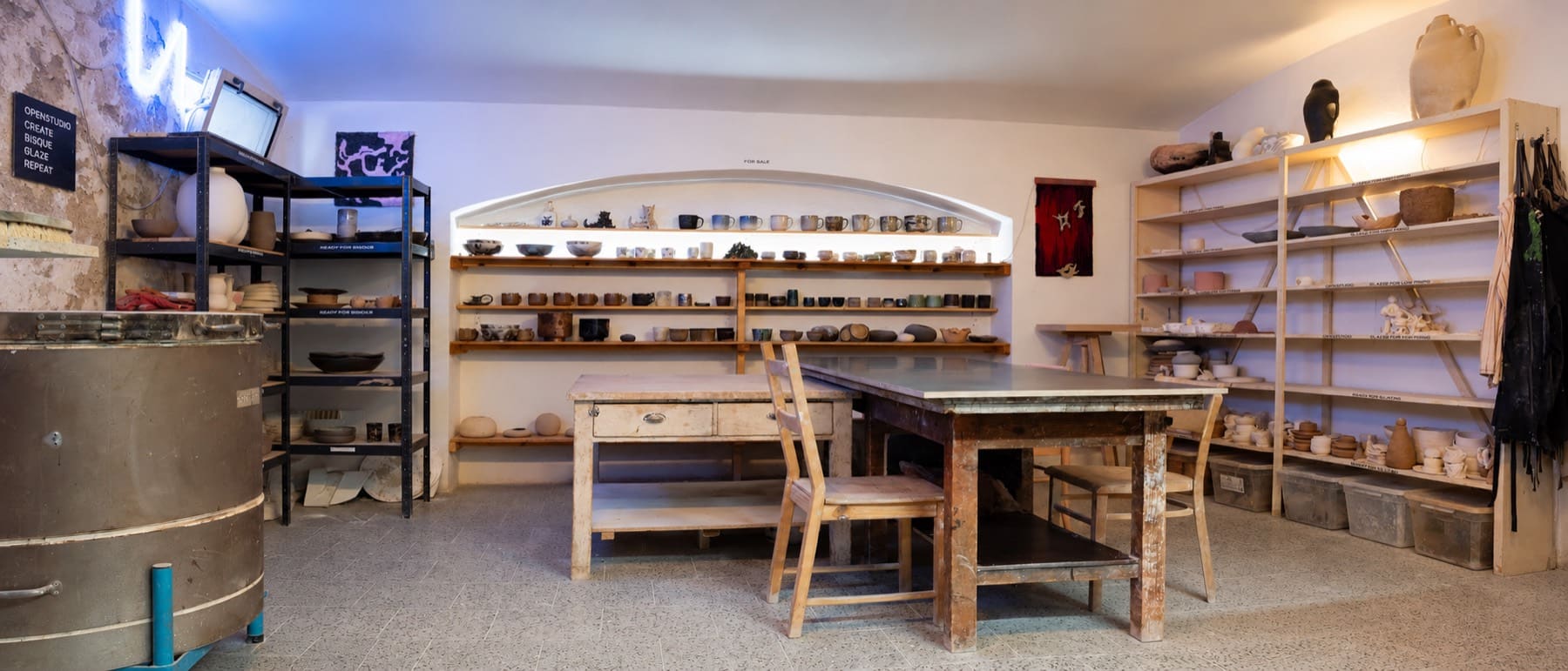 Hlinotéka main space: kiln, shared work tables and shelves of finished work